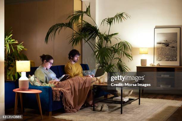 couple using wireless technologies at home - couple at table with ipad stockfoto's en -beelden