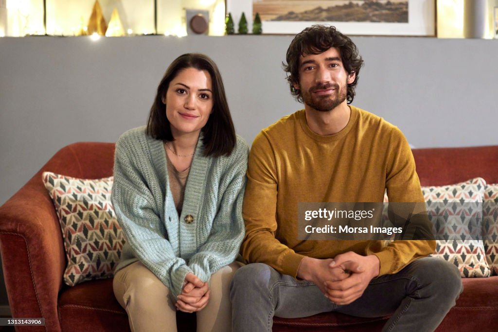 Smiling Mid Adult Couple Sitting On Sofa At Home
