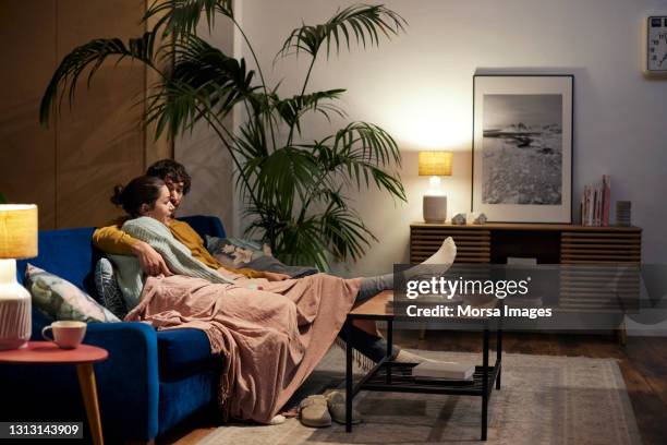couple talking while watching tv in living room - mid adult couple stock pictures, royalty-free photos & images