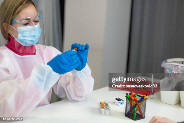 young female healthcare worker shows a new covid-19 vaccine to a patient - pneumococcus stock pictures, royalty-free photos & images