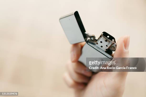 hand holding a vintage metal windproof lighter - feuerzeug stock-fotos und bilder