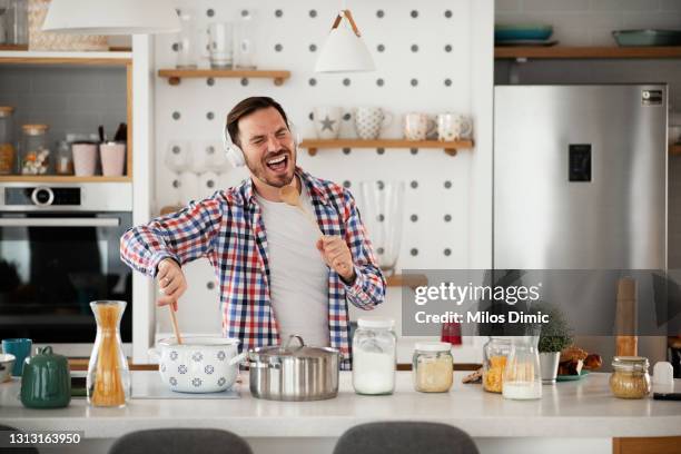 attractive young man dancing and singing in the kitchen stock photo - man cooking stock pictures, royalty-free photos & images