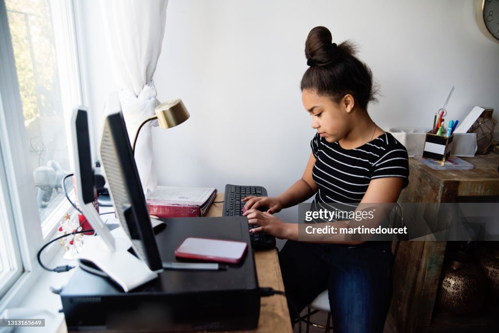 Preteen girl homeschooling on the family desk computer.