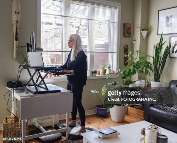donna matura che lavora al computer da casa - lavoro a domicilio foto e immagini stock