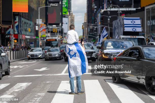 Son sitting on his father's shoulder wearing an Israeli flag stands in Times Square during celebrations marking Israel’s 73rd Yom Ha’Atzmaut amid the...
