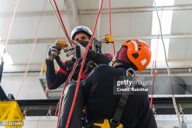 instructeur et étudiant sur la corde pendant le travail à la formation de hauteur - rope high rescue photos et images de collection