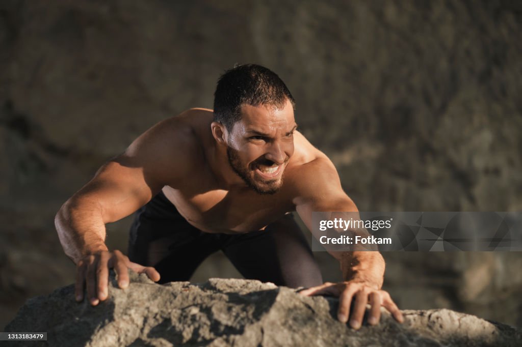 Een jonge mannelijke atleet beklimt een rots.