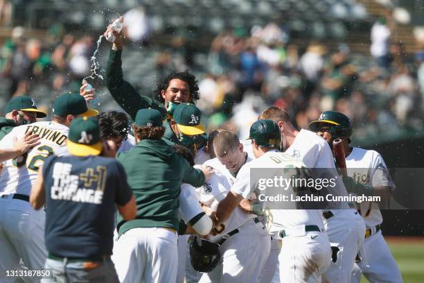 Mitch Moreland of the Oakland Athletics is mobbed by teammates after hitting into a fielding error to score teammate Matt Olson and win the game...