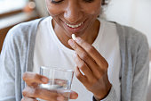Close up happy young african american young woman taking vitamins.
