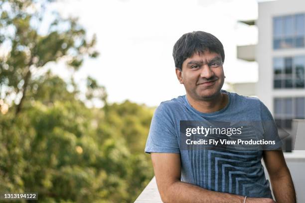 portrait of smiling indian man on apartment patio - tree man syndrome stock pictures, royalty-free photos & images