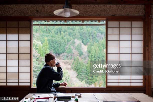 senior japanese artist drinking tea looking out the window - washitsu stock pictures, royalty-free photos & images