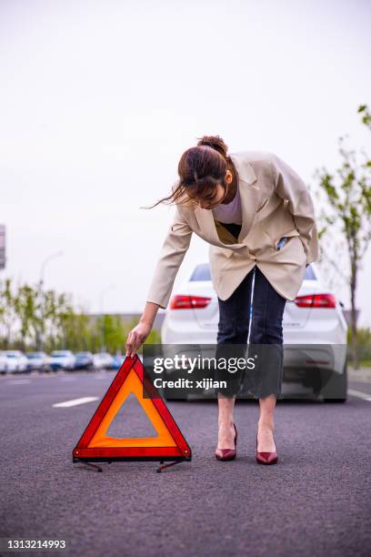 women placing red warning triangle - damaged vehicle stock pictures, royalty-free photos & images