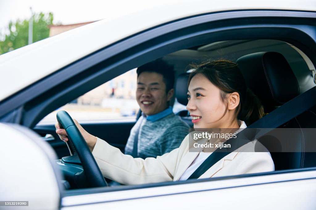 Young woman driving a car with his friend