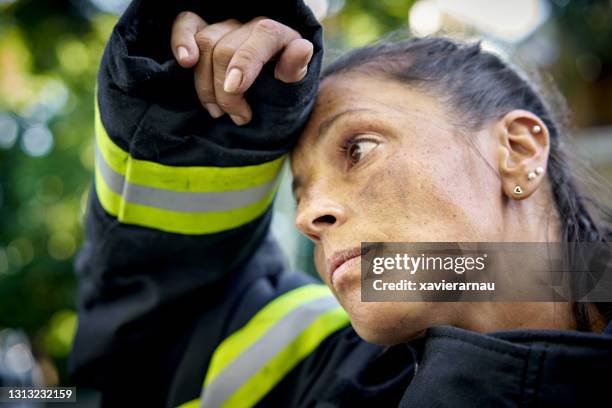 candid portrait of exhausted hispanic female firefighter - firemen at work stock pictures, royalty-free photos & images