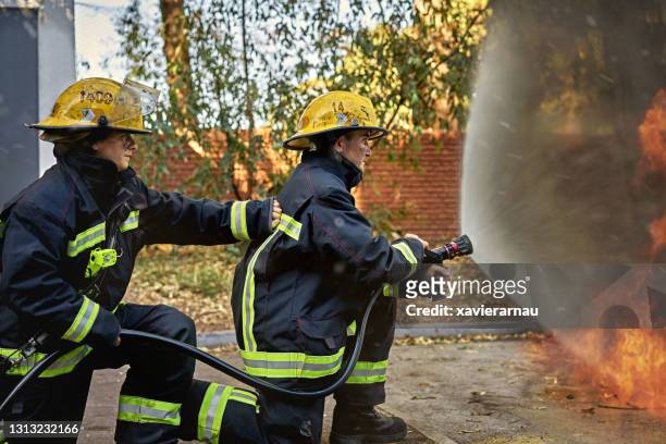 hose team using fog nozzle and wide-angle cone spray pattern - spray nozzle stock pictures, royalty-free photos & images