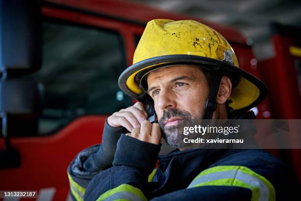 bearded firefighter in mid 40s putting on helmet - get dressed male stock pictures, royalty-free photos & images