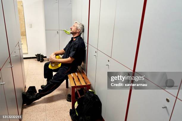 mature male firefighter resting in fire station locker room - firemen at work stock pictures, royalty-free photos & images