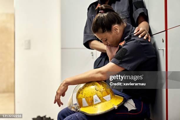 compañero de equipo consolando a mujer bombero exhausta - emergency services fotografías e imágenes de stock