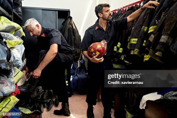 caucasian male firefighters dressing for emergency call - firefighter getting dressed stock pictures, royalty-free photos & images