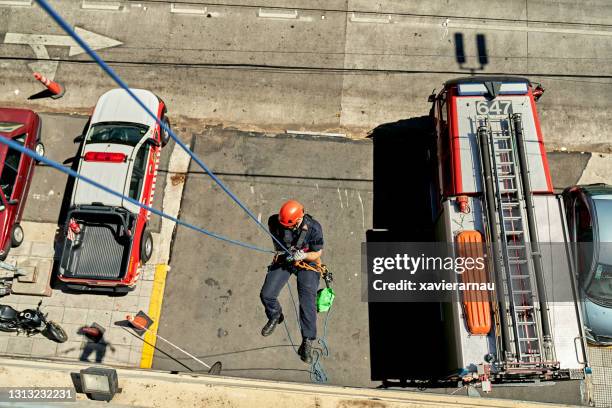 high angle view of male firefighter rappelling down building - training center stock pictures, royalty-free photos & images