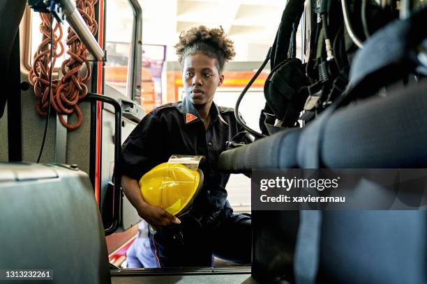 pompiere donna nera con casco imbarco motore antincendio - firefighters foto e immagini stock