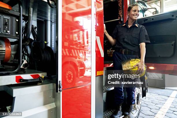 portrait of late 30s female firefighter boarding fire engine - leanincollection stock pictures, royalty-free photos & images