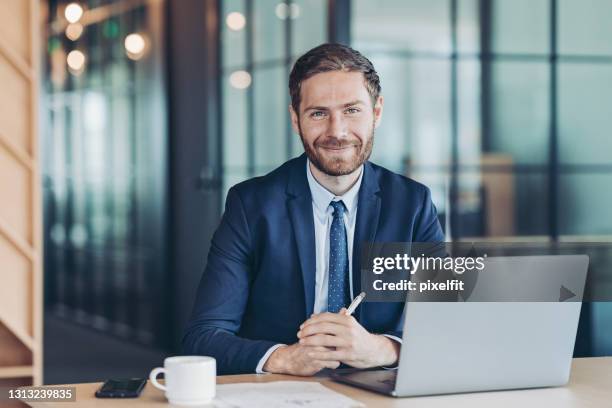 junger geschäftsmann sitzt an seinem schreibtisch im büro - business suit tie stock-fotos und bilder