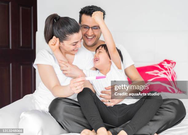 la alegre pareja y su hijo pequeño obtuvieron resultados positivos en la prueba de embarazo. celebración del resultado positivo de la prueba de embarazo en el hogar - second test fotografías e imágenes de stock