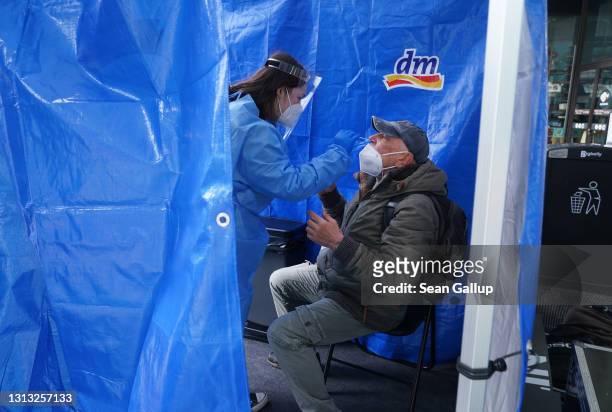 Medical worker takes a nasal swab of a man seeking a Covid test at a Covid testing station operated by German drugstore chain DM at a press event at...