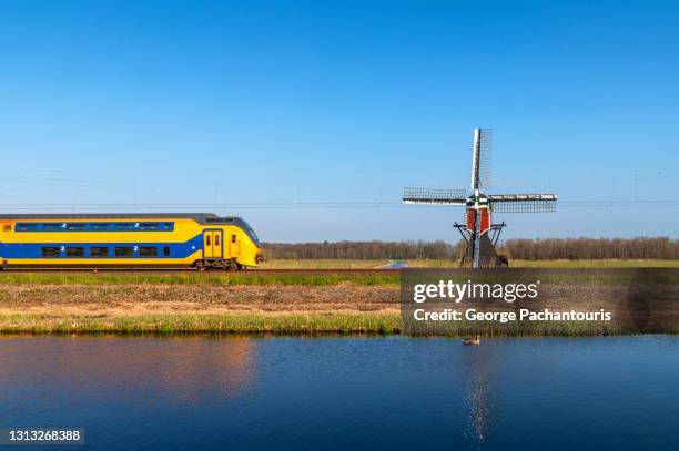 traditional dutch windmill and train moving fast - trein nederland fotografías e imágenes de stock