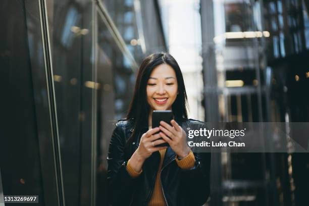 asian cheerful woman using smartphone on the street - mulher chinesa imagens e fotografias de stock