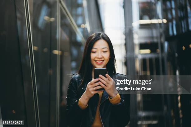 asiatisk glad kvinna som använder smartphone på gatan - chinese ethnicity bildbanksfoton och bilder