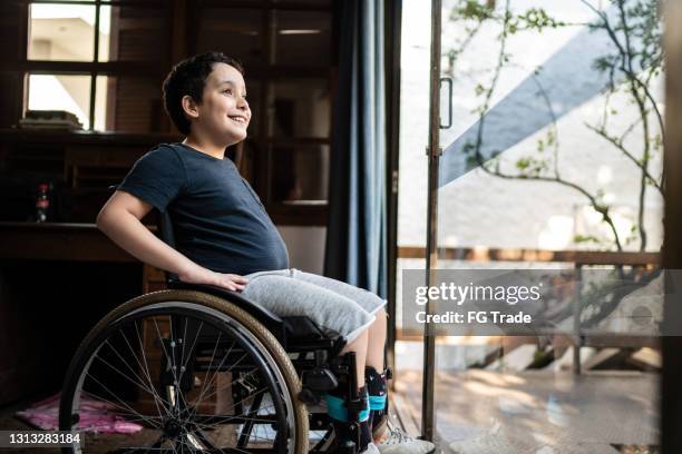 wheelchair boy looking away contemplating at home - one boy stock pictures, royalty-free photos & images