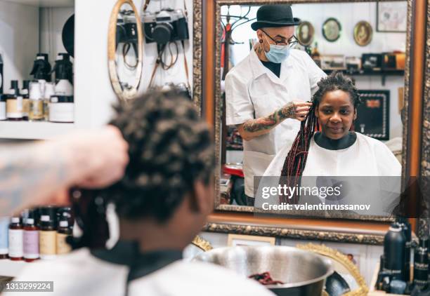 mannelijke kapper die beschermend gezichtsmasker draagt en dreadlocks van afrovrouwen in kapsalon snijdt - dreadlocks stockfoto's en -beelden