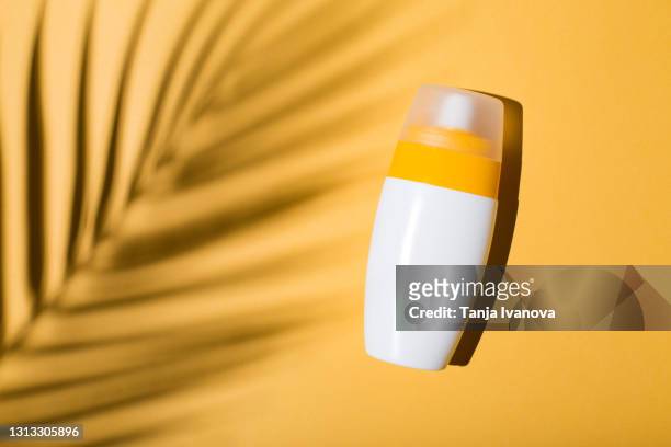 sunscreen on a yellow background with shadow of tropical leaf. flat lay, top view. - suntan lotion stock-fotos und bilder