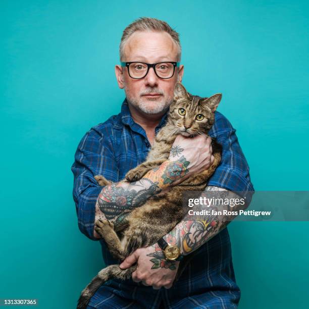 middle-aged man holding a cat - feline stock pictures, royalty-free photos & images