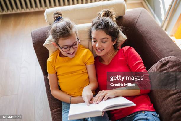 mother and daughter reading a book in living rom - class rom stock pictures, royalty-free photos & images