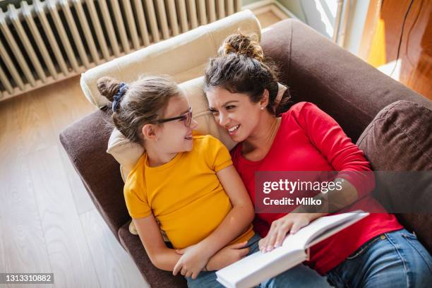 mother and daughter reading a book in living rom - class rom stock pictures, royalty-free photos & images