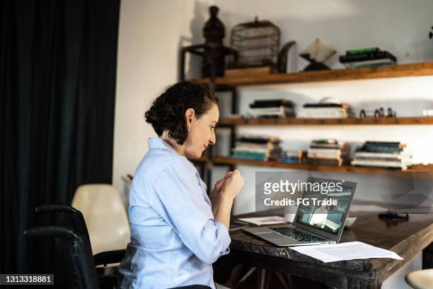 de vrouw die van de handicap een virtuele bedrijfsvergadering thuis doet - looking at camera stockfoto's en -beelden