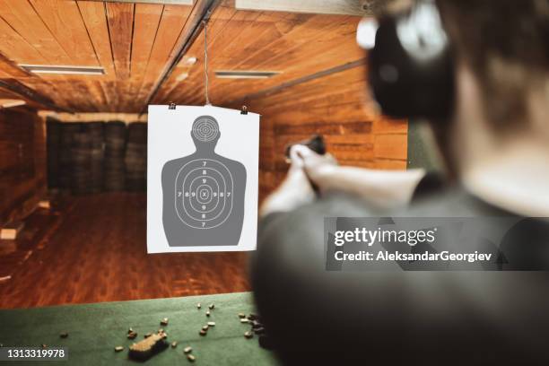 hombre enfocado tratando de puntuar alto en el campo de práctica de armas - shooting fotografías e imágenes de stock