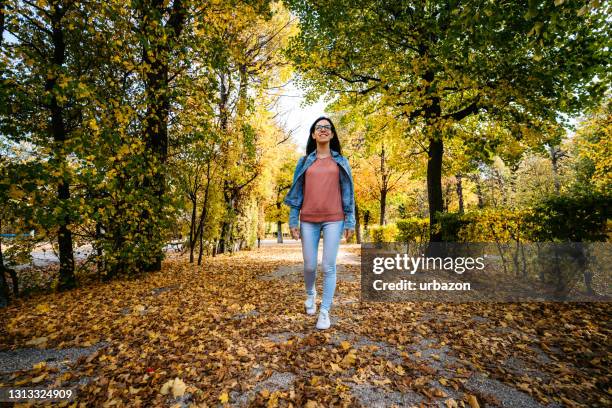 vrouw die in een park loopt - multi coloured trousers stockfoto's en -beelden