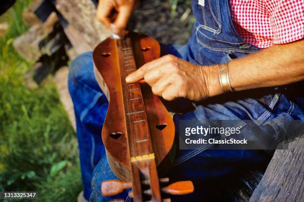 1960s 1970s Man Hands Playing A Mountain Dulcimer In Mountains In Nc Primitive Musical Instrument .