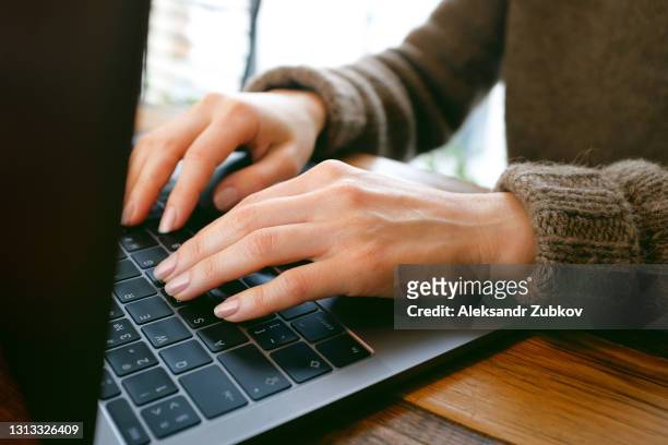 women's hands type text on the keyboard of a computer or laptop. an office worker at his desk, in a coworking space, or in a cafe. the concept of business, freelancing, working from home. communication and acquaintance through social networks, blogging. - russian business woman stock-fotos und bilder