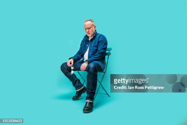 sad looking middle-aged man, looking down - guy sitting stock pictures, royalty-free photos & images