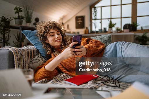 Frau mit Smartphone für Social-Media-Laying in ihrer Couch Frau mit Smartphone für Social-Media-Laying in ihrer Couch