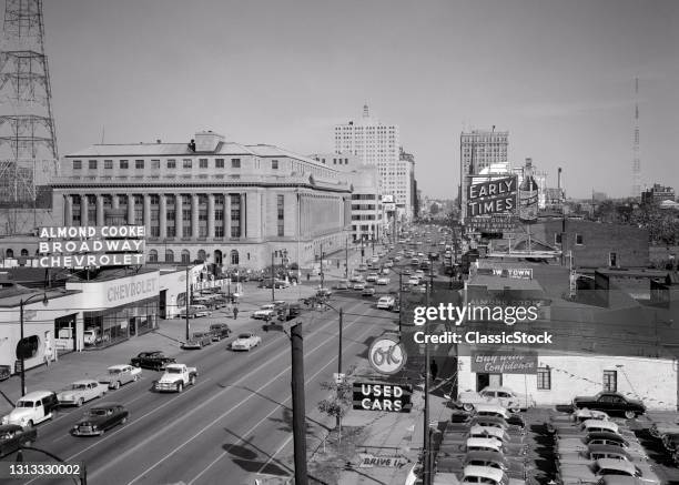 1950s Skyline View Broadway Traffic Ok Used Car Lot In Foreground Billboard Early Times Bourbon Louisville Kentucky USA.