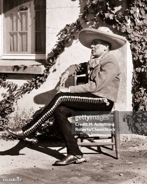 1930s Man Sitting Wearing Typical Charro Costume Sombrero Leather Jacket Boot Spurs Pants Silver Ornamentation Embroidery Mexico.