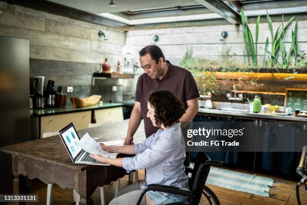 couple doing finances at home - woman with disabilities - bill assistance stock pictures, royalty-free photos & images