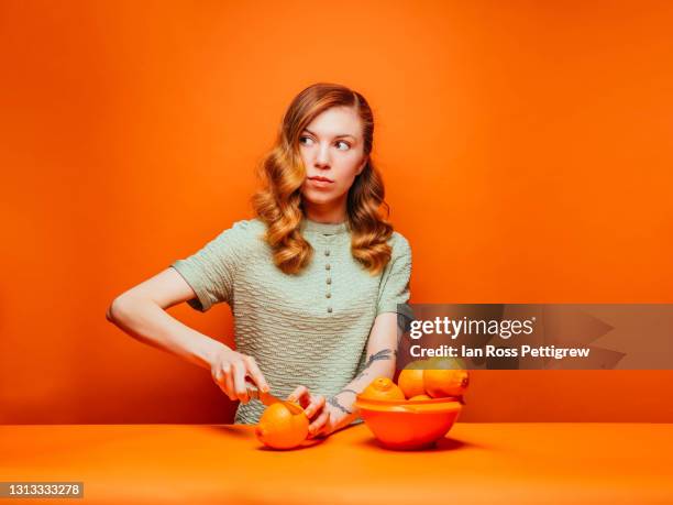 cute young woman slicing oranges - fruits table top stock-fotos und bilder