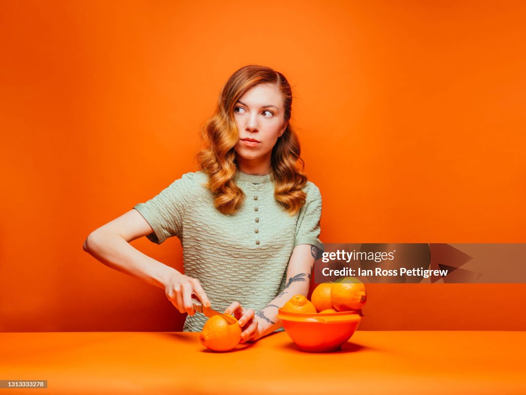 Cute Young woman slicing oranges